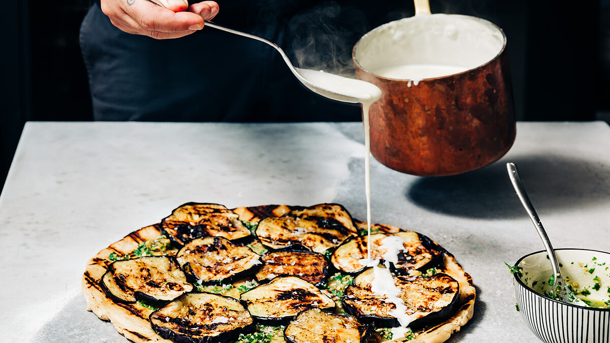 Close up of drizzling sauce on eggplant cooked on grill